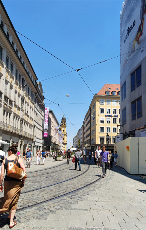 Theatinerstraße in Munich, Germany, looking north toward the distinctive yellow facade and dome of the Theatine Church (Theatinerkirche) in the distance